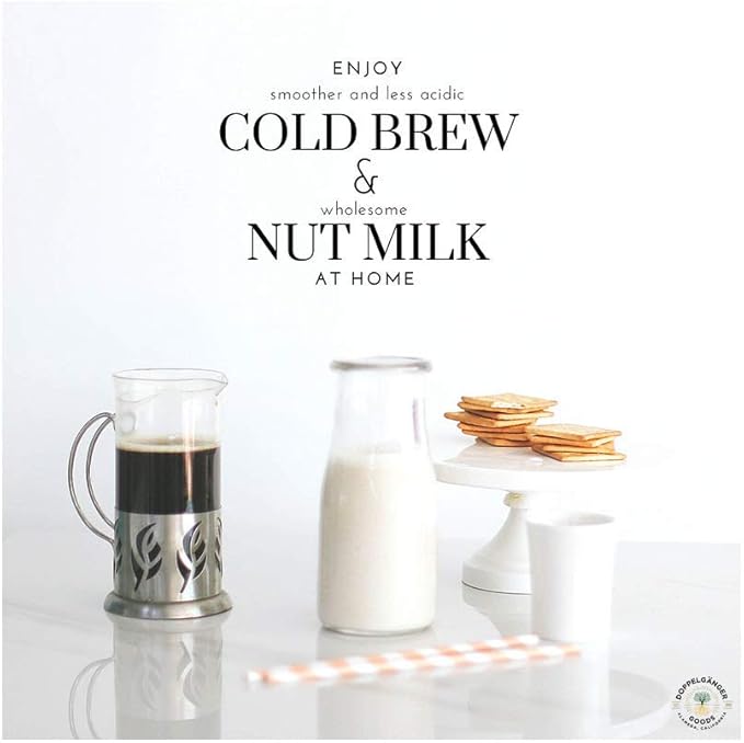 Cold brew coffee in glass pot, nut milk in bottle, cookies on white cake stand on white table